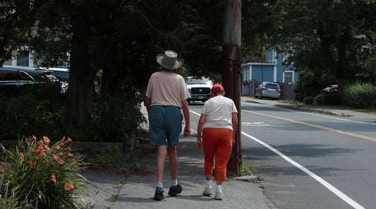 Elderly couple walking with stooped posture and hunched forward.