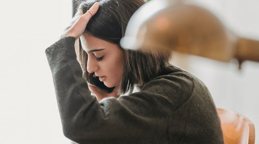 Woman in poor posture holding her head in discomfort, illustrating posture's effect on the nervous system.