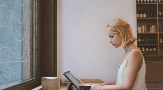 Seated woman looking down at laptop, showing typical cause of poor posture.