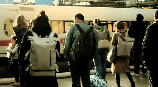Travelers waiting for a train, slouching with heavy bags.