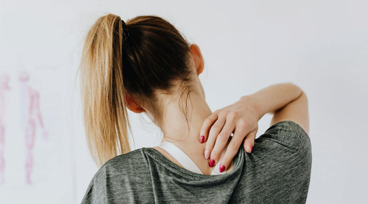 Woman touching her upper back, illustrating posture support focus.