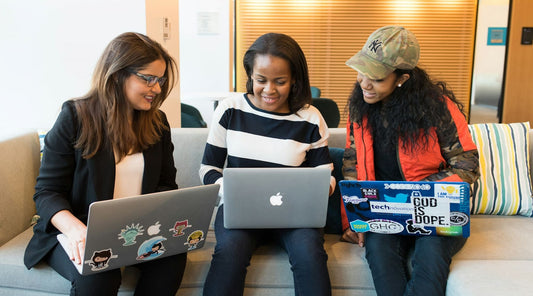 Three women collaborating with laptops.