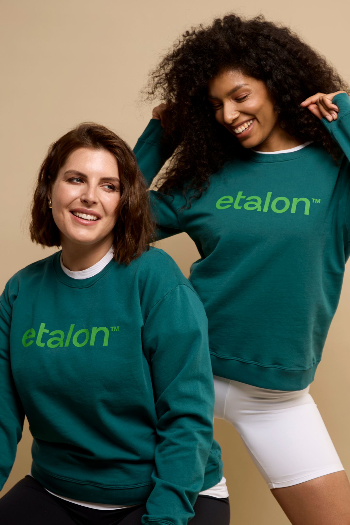 Two women wearing green Etalon sweatshirts in a relaxed, everyday setting to highlight the casual fit.