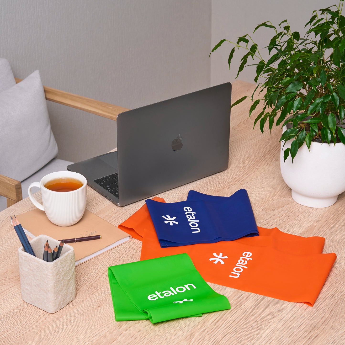 A set of green, orange, and blue Etalon latex bands displayed on a desk.
