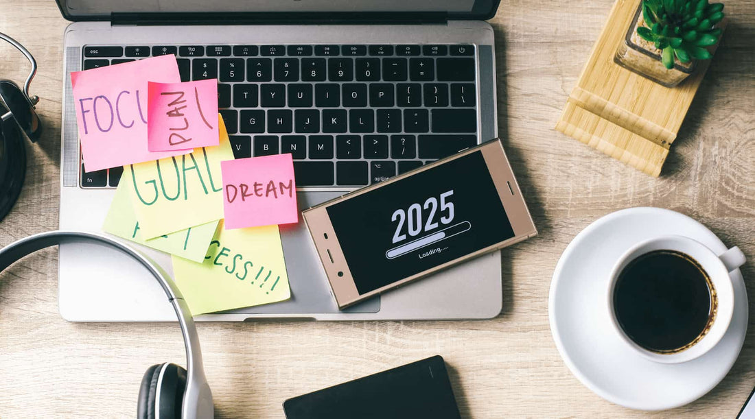 Creative flat lay of laptop, goal-oriented sticky notes, coffee cup, and phone screen marked 2025 symbolizing women’s wellness resolutions and barriers.