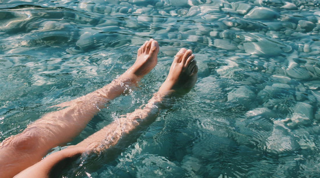 Person’s feet in water, symbolizing grounding and posture connection.