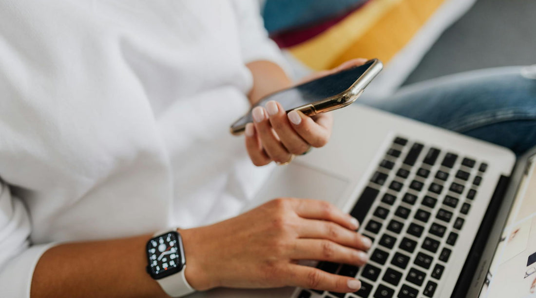 Person holding a smartphone, using a laptop, and wearing a smartwatch symbolizing posture-monitoring technology.