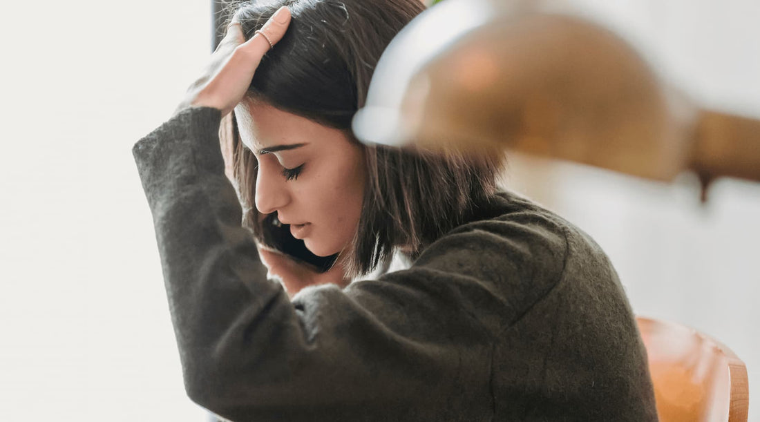 Woman in poor posture holding her head in discomfort, illustrating posture's effect on the nervous system.