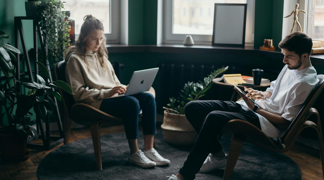 Man and woman working on devices while slouching, showing impact of poor posture on productivity.