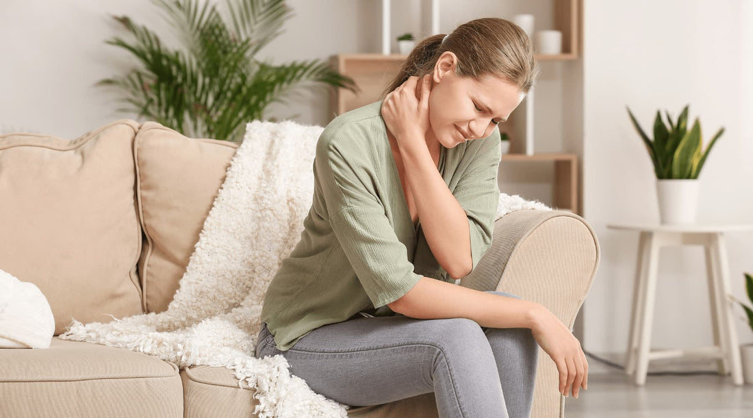 Female experiencing back and neck discomfort while sitting, illustrating posture-related chronic pain.