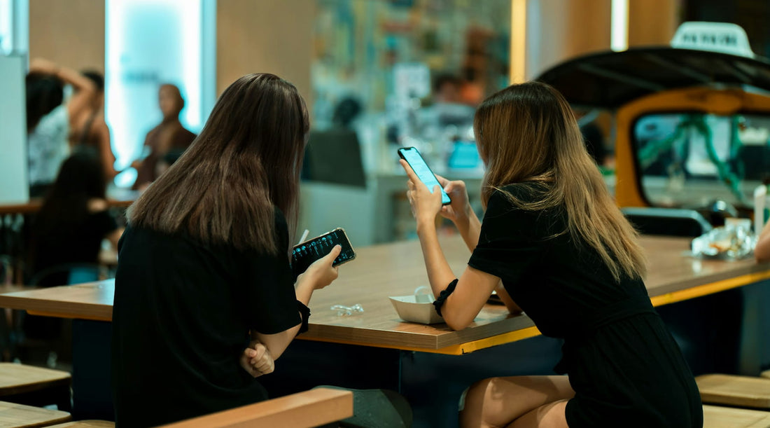 Women hunched over smartphones, illustrating posture strain from device use.