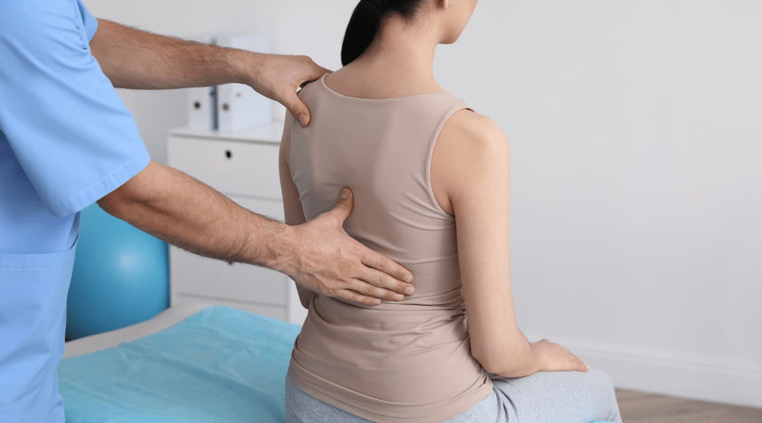 Woman sitting while a professional checks her back, representing Etalon posture bra’s role in spinal care.