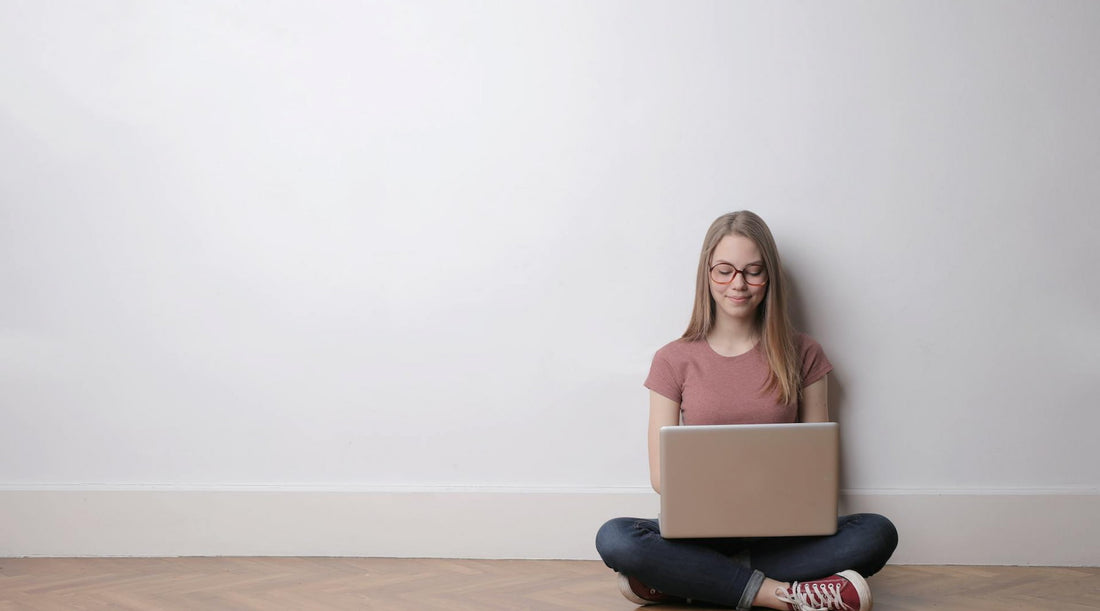Woman sitting cross-legged on the floor using a laptop, reflecting posture benefits.