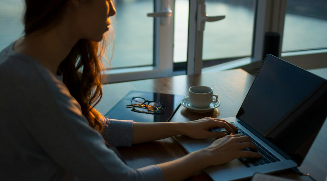 Woman hunched over while working at a desk with laptop.