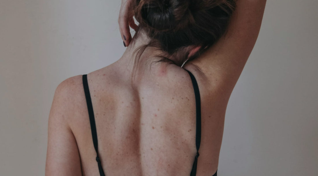 Back view of woman touching her neck, illustrating pain from misalignment.