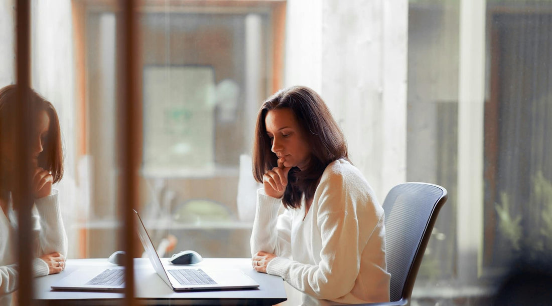 Woman sitting at desk with laptop, displaying sway back posture.