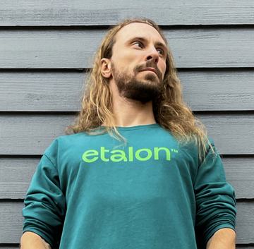 A man wearing green Etalon sweatshirt, illustrating posture correction and upper‐back support for men.