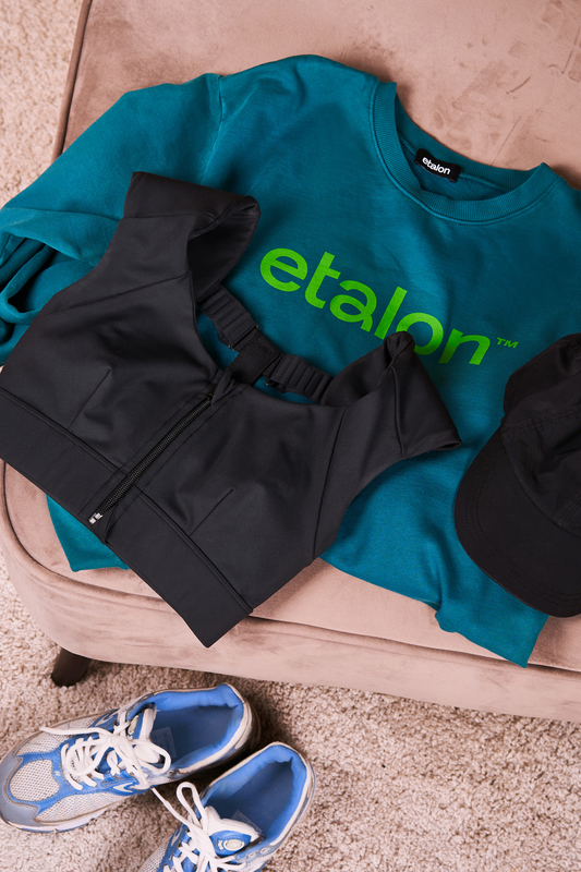 Etalon sweatshirt arranged in a flat lay with a posture bra and sneakers to showcase a casual style.